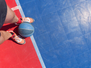Basketball player with ball on a outdoor court.