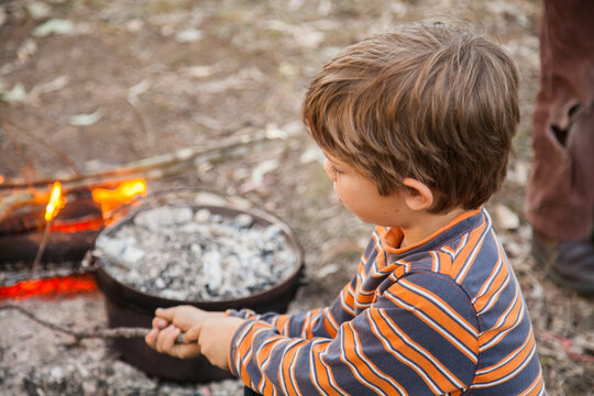Young boy toasting a marshmallow on a campfire