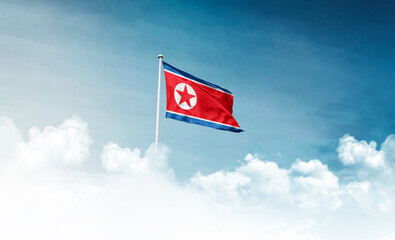 North Korea national flag with mast waving in beautiful sky. Korea flag for Republic Day and Independence Day.