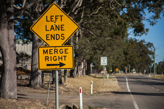 Orange left lane ends merge right sign with an arrow on the roadside