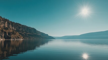 Serene lake reflecting mountain peaks under a bright sun