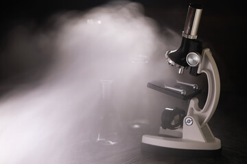 Microscope on Dark Background with Fog and Laboratory Glassware