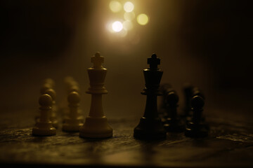 White and Black Chess Pieces on a Wooden Board with Warm Lighting in the Background