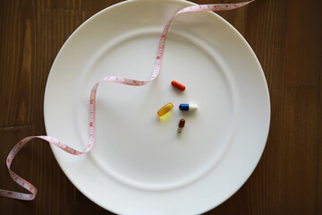 Diet and Nutrition Concept with Pills on Plate and Measuring Tape