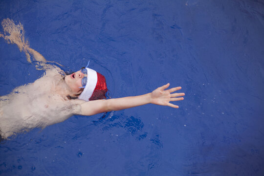Teenage boy in Santa hat celebrating christmas in a pool
