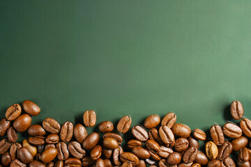 A display of roasted coffee beans scattered on a green background.