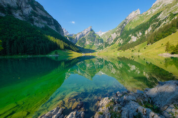 Seealpsee, Switzerland. Lake and reflections on the water surface. Mountain landscapes in summer. Place for mountain hiking, travel and vacation. Wallpaper, postcard, photo.