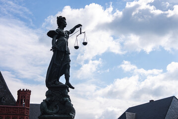 The Fountain of Justice statue in Frankfurt, Germany, with Lady Justice holding scales, set against...