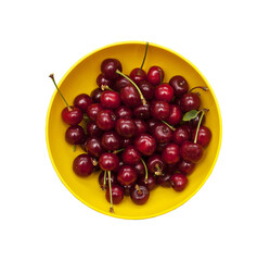 Ripe cherries in a yellow round bowl isolated