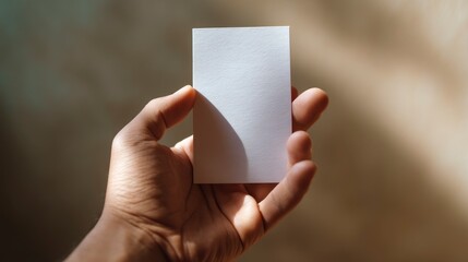 Hand holds a blank white card outdoors with a soft-focus, warm, sunny, and inviting backdrop.