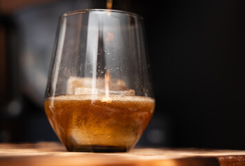 A frosty glass of beer is resting on a sturdy wooden table surface