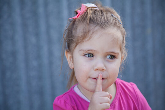 Young child with finger to her lips saying shhh