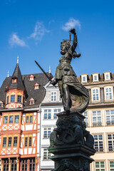 The Fountain of Justice in Frankfurt's Romerberg square, featuring Lady Justice with scales and sword, framed by traditional half timbered buildings.