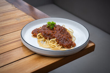 Delicious spaghetti bolognese on white plate on cafe table.