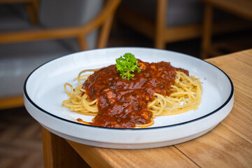 Delicious spaghetti bolognese on white plate on cafe table.