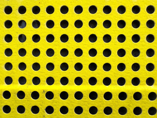 Yellow perforated surface with uniform circular patterns for industrial design