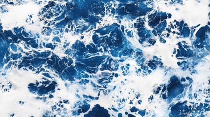 Obraz premium Aerial view of foamy ocean waves in deep blues and white, dynamic nature scene.