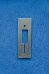 A metal sign on a blue wall indicating a men's toilet