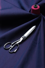 Professional sewing scissors rest atop a bolt of deep blue denim fabric, representing craftsmanship, fashion tailoring, and precision in garment-making.
