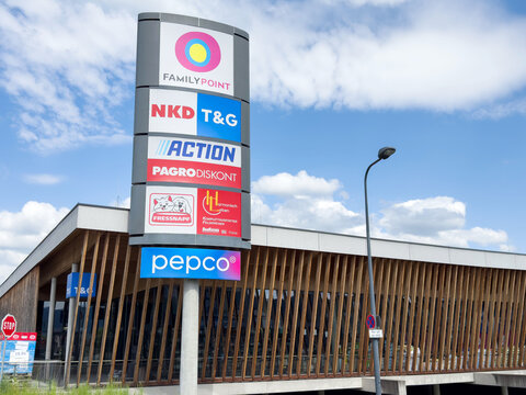 Shopping center exterior with retail signs on modern building against blue sky