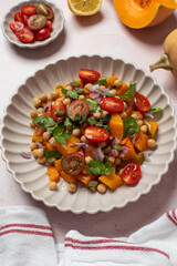 Autumn warm chickpea and roasted pumpkin salad with fresh cherry tomatoes and herbs. Vegan meals