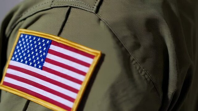 Close up details of an american flag patch sewn onto the sleeve of a military uniform, symbolizing patriotism, service, and national identity