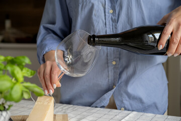 Pour white wine, champagne or prosecco into a glass from a bottle for an aperitif on the terrace	