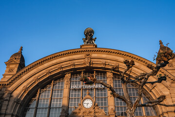 The facade of Frankfurt Hauptbahnhof in Germany features a grand arched window, a central clock,...