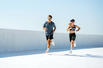 Runners sprinting along a bright, modern track under a clear blue sky at midday
