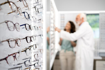 Eyeglasses for sale in optics store and optician helping customer to choose the best frame.