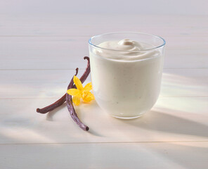 Vanille Dessert mit Quark mit Vanille Bluete und Vanille Stange auf hellem Holzfond, Nachspeise, isoliert, s&uuml;ss, 