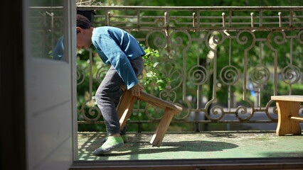 Young boy sitting on a small stool on the balcony, legs stretched out, enjoying a peaceful moment...