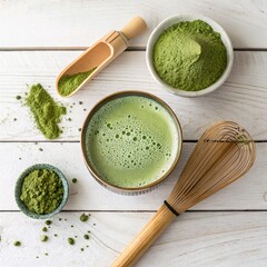 **Flat lay of a matcha latte** in a ceramic cup, surrounded by matcha powder, whisk, and a wooden spoon.
