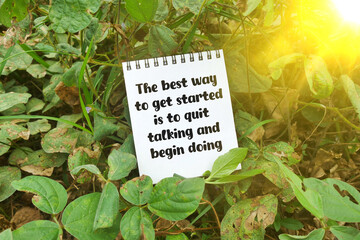 Notebook with quote 'The best way to get started is to quit talking and begin doing' on forest ground