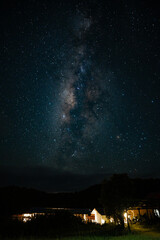Beautiful Milky Way galaxy shining brightly in the night sky above a small countryside house, illustrating the breathtaking beauty of the universe, stargazing, astronomy, and cosmic wonder
