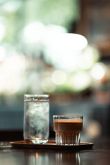 refreshing glass of iced water and dirty coffee served on rustic wooden table in a cozy cafe with soft daylight ambiance, perfect for relaxation and inspiration.