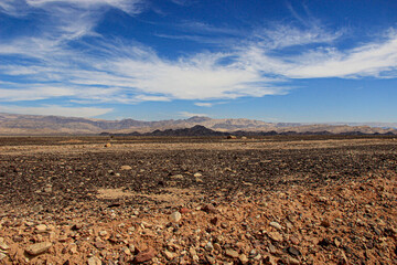 Panoramic view of the landscape of Jordanian nature and mountains against a backdrop of bright blue sky and cirrus clouds.