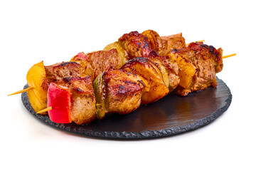 Grilled meat skewers with vegetables on slate plate, isolated on white background.