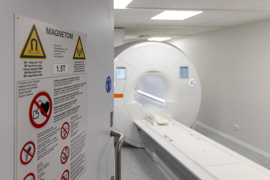 MRI scanner room entrance with multilingual safety warning signs. Modern hospital magnetic resonance imaging technology for medical diagnostics and patient care.