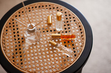Liquid home perfume in glass bottle with bamboo sticks on rattan table in room close up. Aromatherapy. Cozy atmosphere.