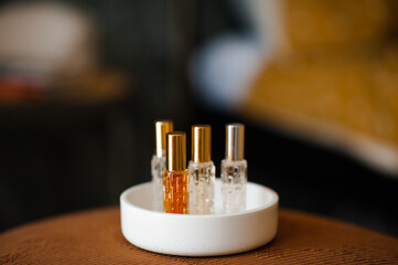 Liquid fragrances in glass bottles in white ceramic tray in room close up. Home cozy atmosphere.