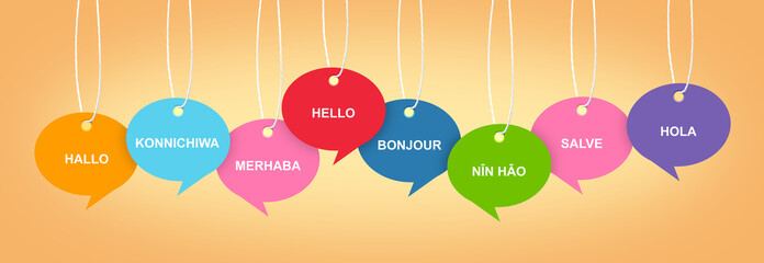 Paper speech bubbles with greetings in different languages hanging on pale orange background. Banner design © New Africa