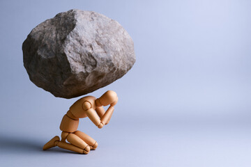 Conceptual wooden figures illustrate concepts of pressure and judgment as figure kneels under large rock symbolizing emotional burden