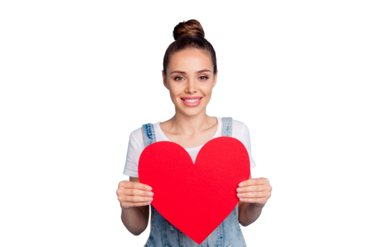 Portrait of pretty girl holding paper card gift for 14-february wearing white t-shirt denim jeans overalls isolated over blue background