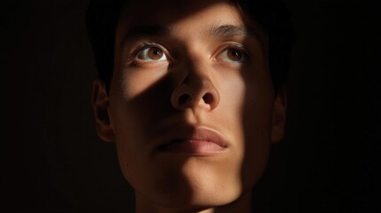 Close-up portrait of a young man's face. the focus is on his eyes, which are looking up towards the sky.