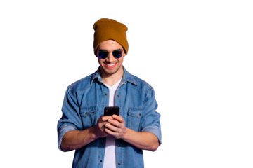 Photo of cheerful kind friendly blogger holding telephone with hands poting news in feed of social media smiling toothily wearing denim jacket isolated over purple vivid color background