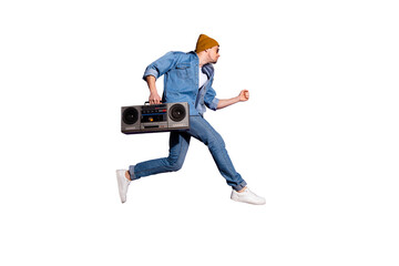 Full length body size photo of urgent handsome guy in jeans denim shirt holding retro audio recorder with hand jumping towards disco isolated over purple violet vivid color background
