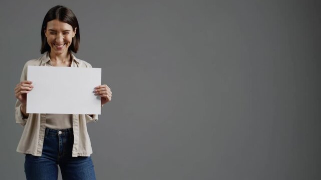 Woman expressively presenting blank sign against neutral background