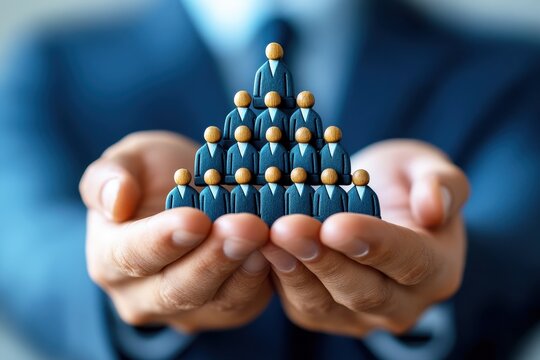 Hands Holding Wooden Figures in Pyramid Formation Representing Leadership, Teamwork, Growth, and Business Success in Corporate Environment