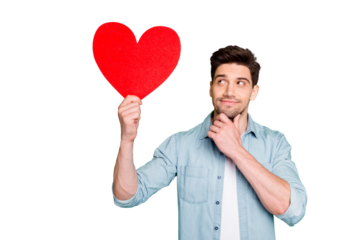 Photo of amazing guy holding large red paper heart thinking over prom invitation for girlfriend have good thought wear denim shirt isolated green color background